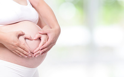 hands in a heart shape on expectant mother pregnant belly