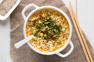instant noodles in a white plate with vegetables and chopsticks