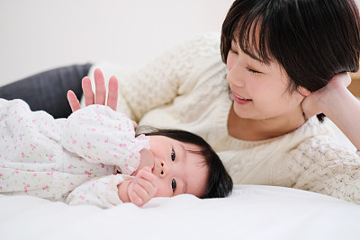 Baby and mother lying on bed