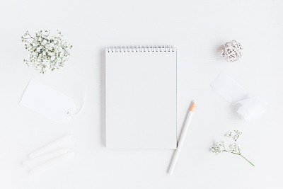 Workspace with notebook, paper blank, gypsophila flowers, pencils
