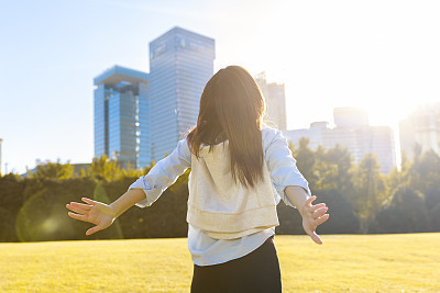 Portrait of Asian young woman with hands raised under sun flare at park,Shanghai,China