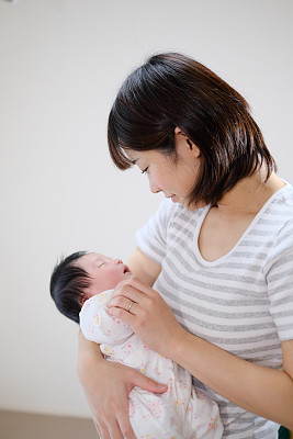 mother embracing newborn baby in arms