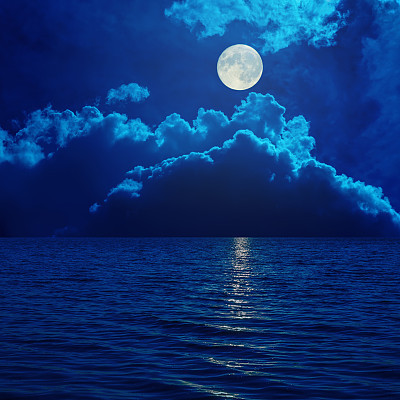 full moon in clouds over sea