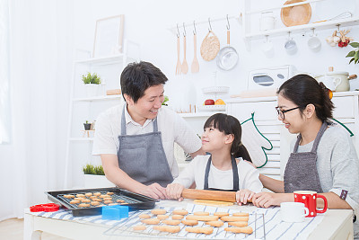 Portrait of little asian girl and her parents baking cake and cookies together in the kitchen. Happy asian family and motherâs day concept预览效果