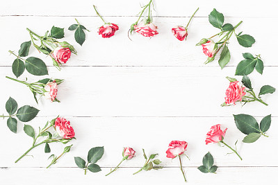 Frame with rose flowers on wooden white background
