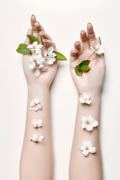Fashion art hand woman in summer time and flowers on her hand with bright contrasting makeup. Creative beauty photo hand girls sitting at table on contrasting background with colored shadows. Skincare