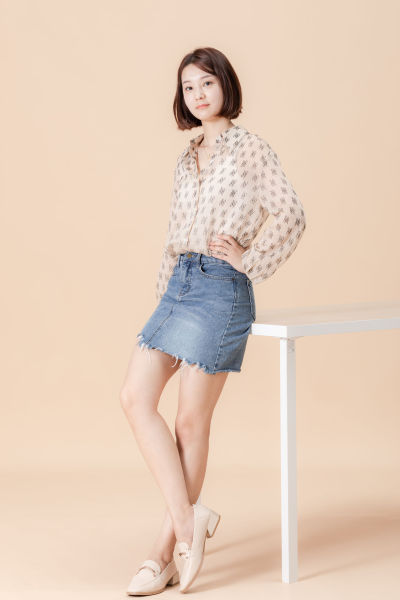 服饰系列实景模特穿着杏色衬衫搭配牛仔短裙、黑色长裤、灰色百褶裙的室内摆拍