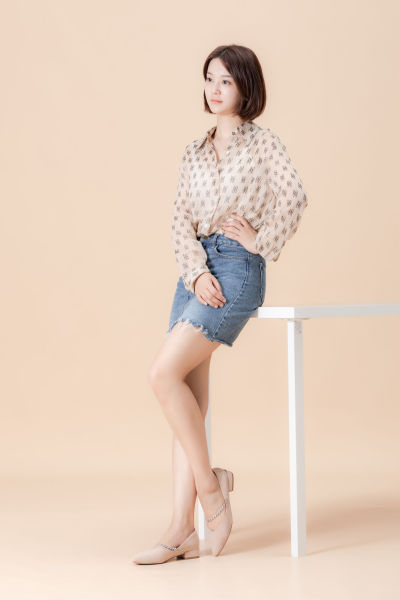 服饰系列实景模特穿着杏色衬衫搭配牛仔短裙、黑色长裤、灰色百褶裙的室内摆拍