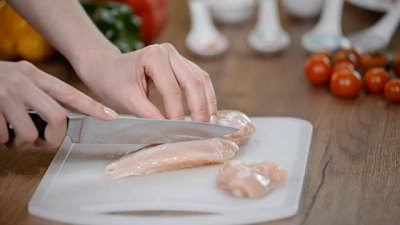 女厨师在木板上切生鸡肉。