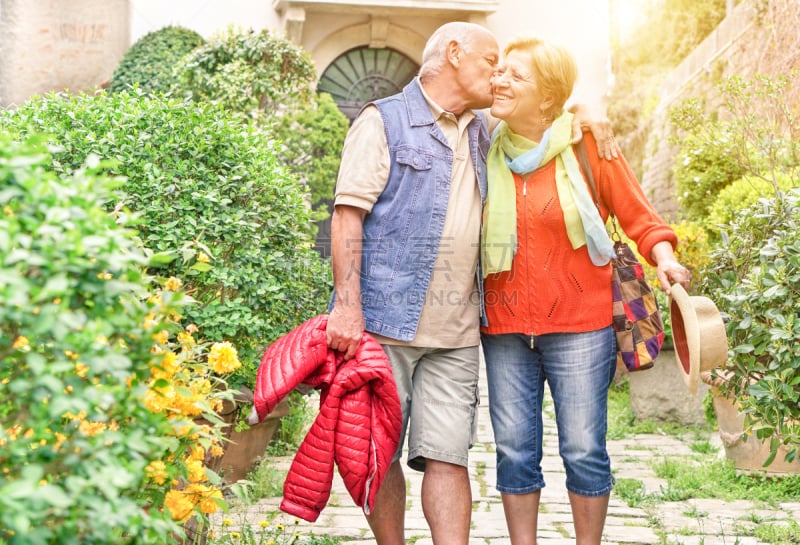 Happy playful senior couple in love tenderly enjoying romantic vacation for wedding anniversary celebration - Joyful elderly active lifestyle - Warm filter with artificial sunlight