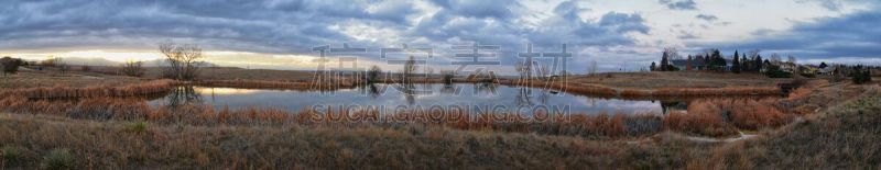 Views of Josh’s Pond walking path, Reflecting Sunset in Broomfield Colorado surrounded by Cattails, plains and Rocky mountain landscape during sunset. United States.