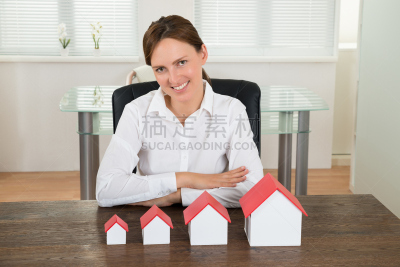 Businesswoman With House Models At Desk