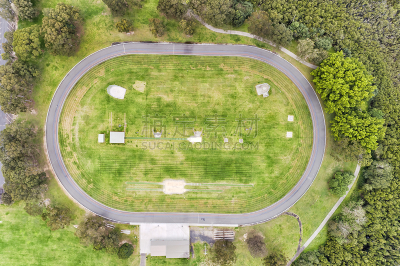 Green oval in Gosford town for athletic sports on a sunny day in the middle of green leafy park – aerial top down view from above.