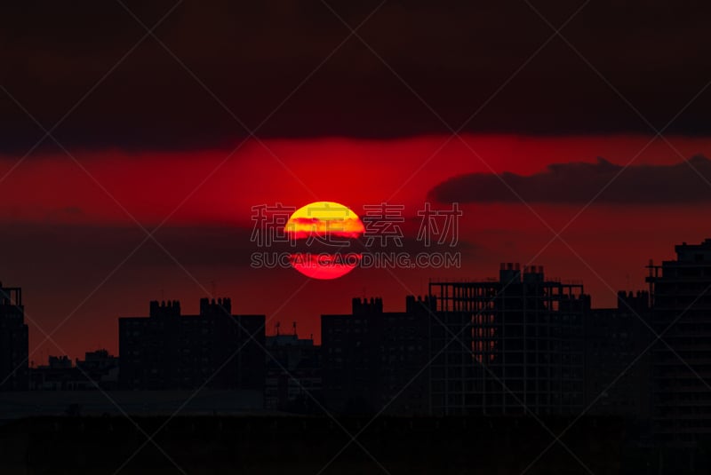 Atardecer con cielo rojizo y gran sol sobre el cielo. Edificios en construcción en la ciudad de Valencia. Comunidad Valenciana.