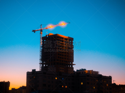 Working construction tower crane building a house at sunrise