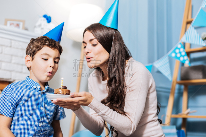 Little boy and his mother blowing out birthday candle