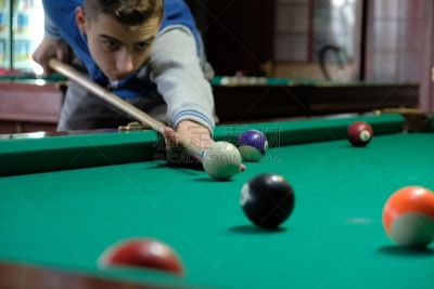 Teen playing in american pool billiard.