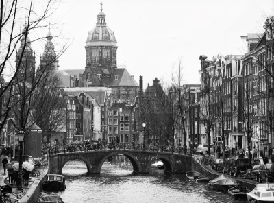 The Oudezijdsvoorburgwal  a street and canal in the Red-light district  in the center of Amsterdam. In the background The Basilica of St. Nicholas.  Black and white
