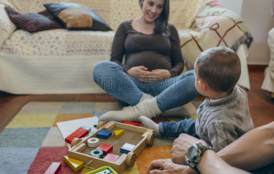 Father playing with toddler while the mother is looking at them