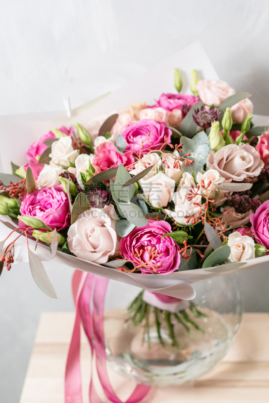 beautiful bouquet of mixed flowers into a vase on wooden table