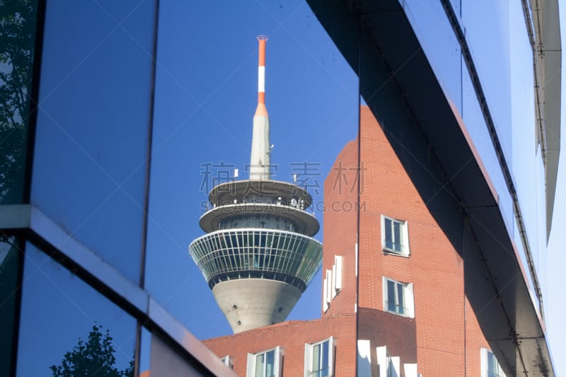 Der Fernsehturm und Geschäftsgebäude spiegeln sich im glänzenden Fenster von einem anderen Bürohaus in Düsseldorf