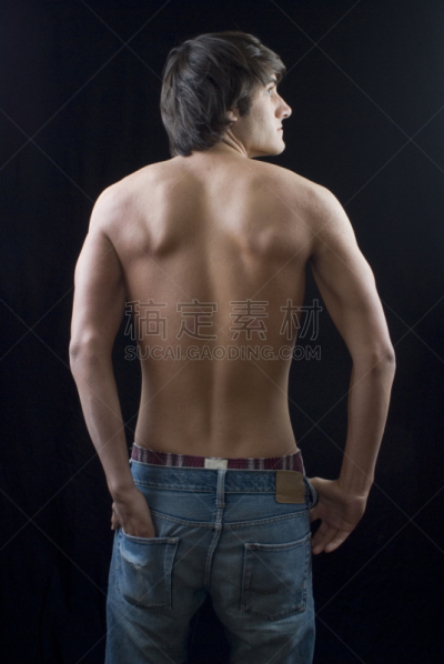 男性,背面视角,男式平腿泳裤,垂直画幅,臀部,棕色头发,牛仔裤,黑色背景,青年人,手放在兜里