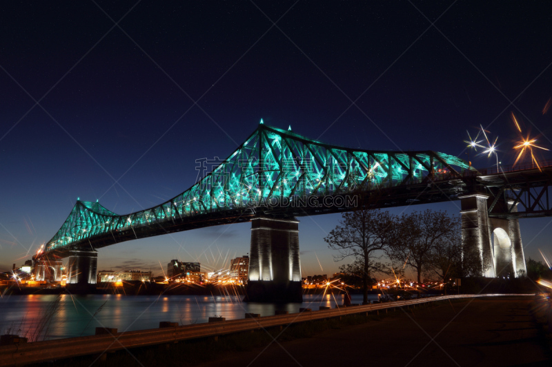 Jacques Cartier Bridge Illumination in Montreal, reflection in water. Montreal’s 375th anniversary. luminous colorful interactive Jacques Cartier Bridge. Bridge panoramic colorful silhouette by night.