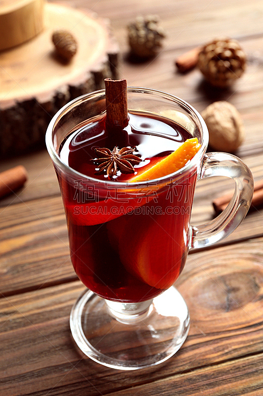 Glass cup of delicious Christmas mulled wine on wooden background, closeup