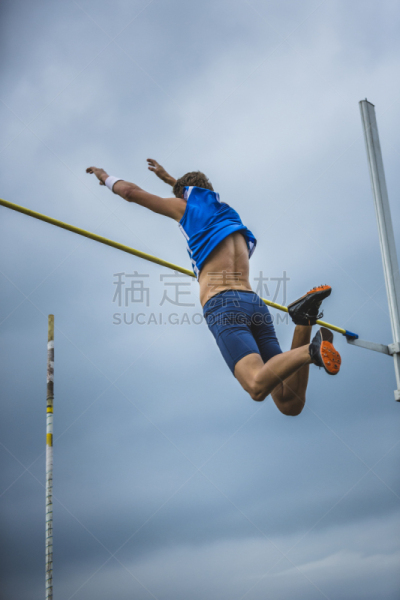 Pole vault male athlete successful attempt over bar