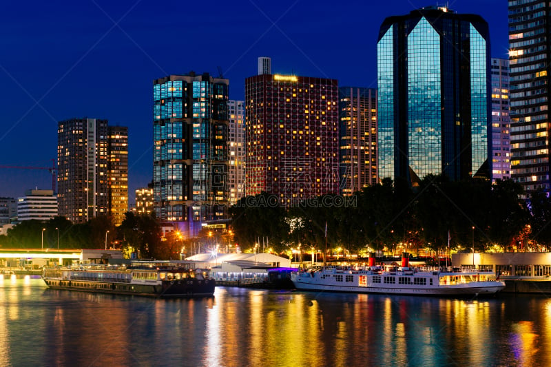 Modern buildings in Paris residential district near the Seine river. Night cityscape with illuminated skyscrapers, city lights reflection. Urban architecture, house building, city construction concept