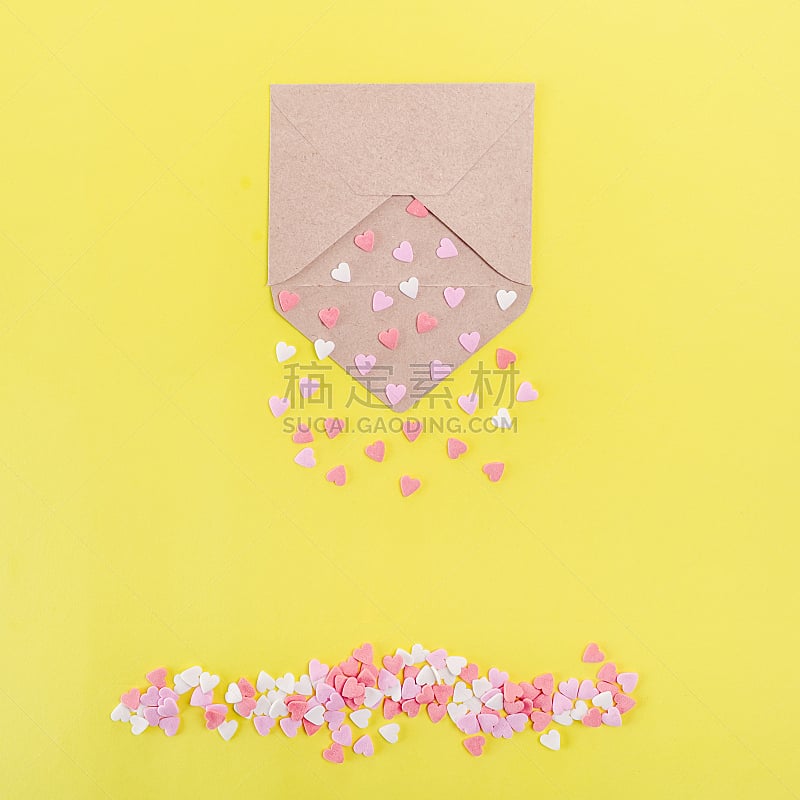 Multicolor sweets sugar candy hearts pour forth of craft paper envelope on bright yellow background . Valentine day. love concept. Gift, message for lover. Space for text. Square card.
