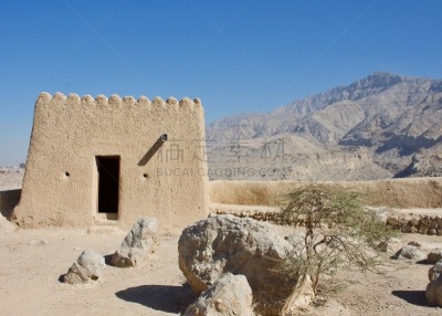Dhayah Fort in Ras al Khaimah in the sunshine with Hajar Mountains in background.