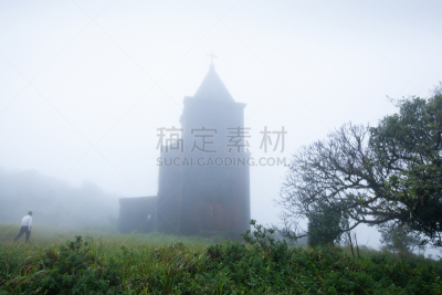 Khmer men walking to the ancient catholic church in the mist of morning, a remote settlement builds by the French colonialists in 1928, a very rare sight in Cambodia. Preah Monivong Bokor National Park, Kampot.