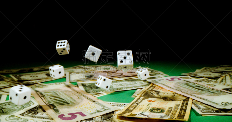 Dice thrown on table covered with dollars