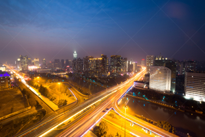 traffic light trails on overpass and cityscape at night