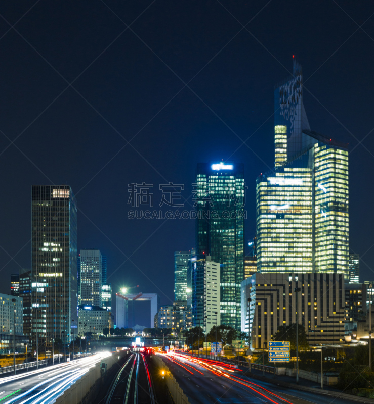 Skyscrapers in Paris business district La Defense. European night cityscape with dynamic street traffic, car lights and glass facades of modern buildings. Economy, finances, transport concept. Toned