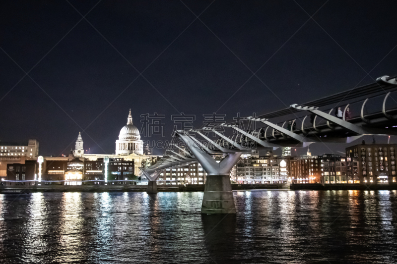 St Pauls Cathedral lit up at night viewed across the River Thames with the Millennium bridge reaching across