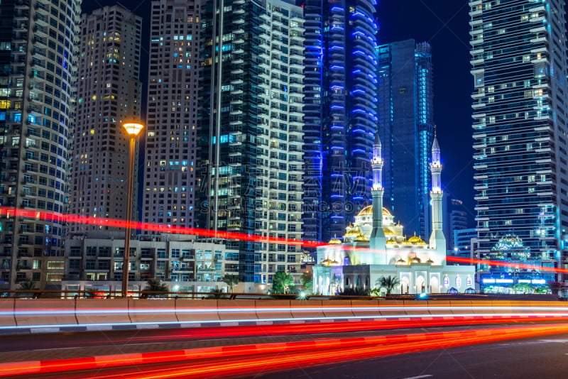 Mohammed Bin Ahmed Almulla mosque with buidings and light trails at night in Dubai, United Arab Emirates