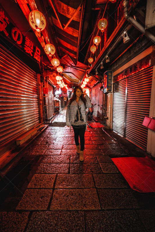 A woman poses on the famous Old Street of Jiufen, Taiwan at night.